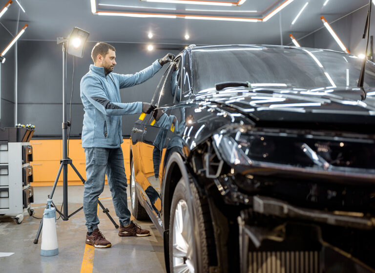 Wide shot of technician applying car window tint