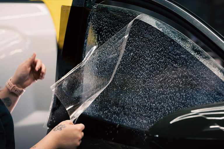 Technician applying car window tint