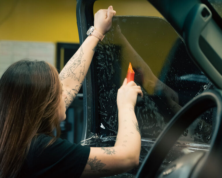 Technician applying car window tint
